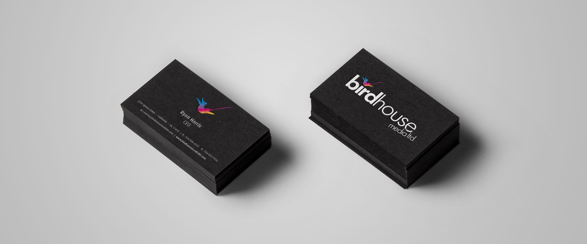 Black business cards, branded with media company logo on the back and contact information with an icon on the front.